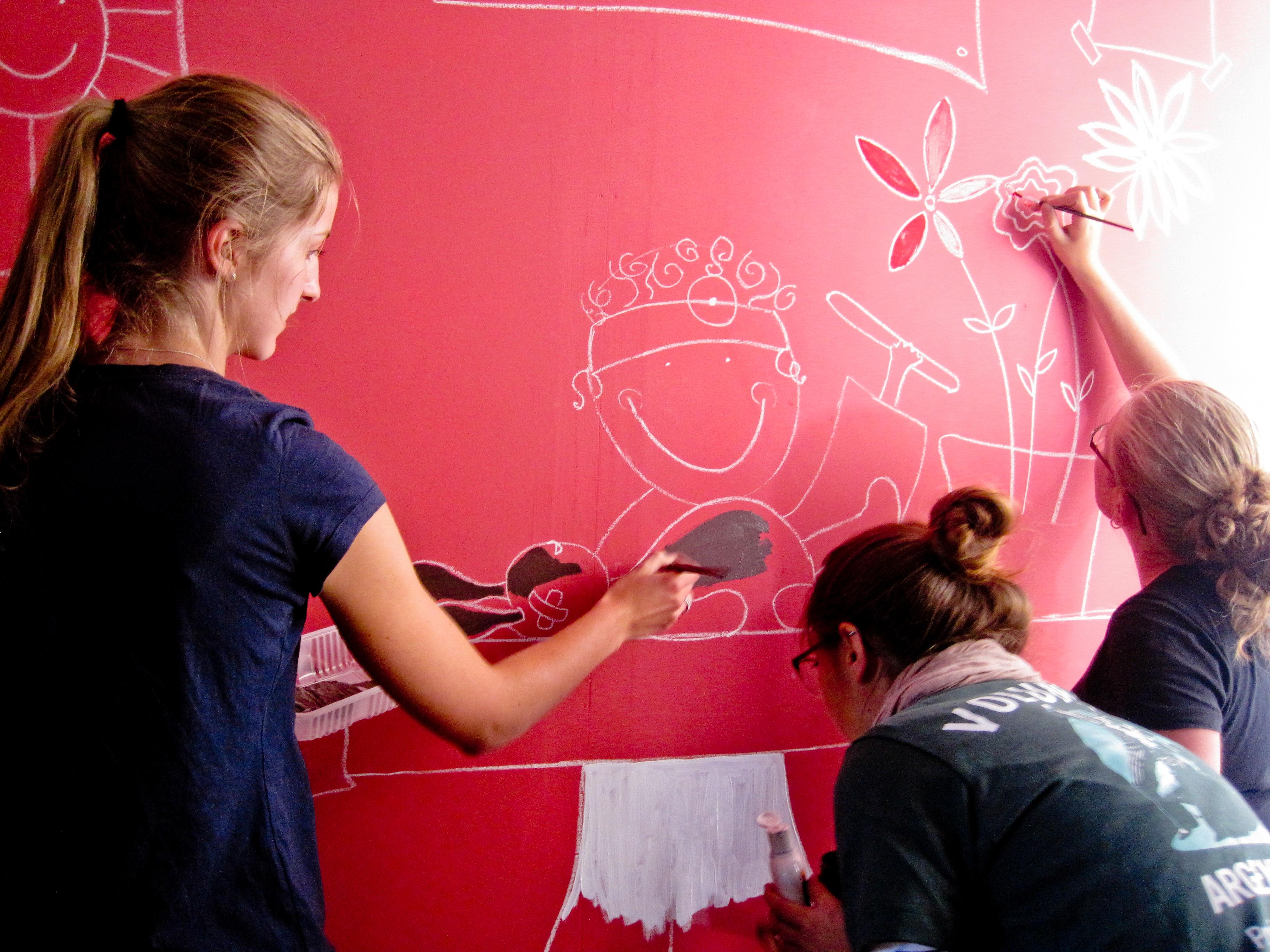 Three Projects Abroad volunteers paint a colourful, educational mural during a community day in Argentina. Projects Abroad Childcare volunteers help paint an educational mural on a wall at a care centre in Argentina.